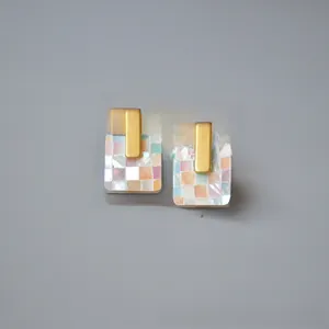 Close-up of matte gold square earrings with colorful mosaic mother of pearl inlay