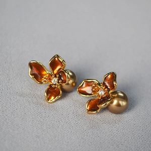 Macro shot of orange enamel flower earrings with champagne pearls and zircon inlay