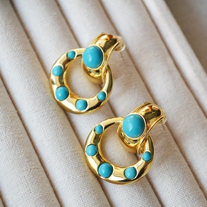 Vintage gold plated brass hoop earrings with inlaid turquoise stones on velvet