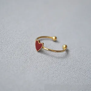 Close-up of gold-plated brass ring with red enamel heart charm and adjustable band