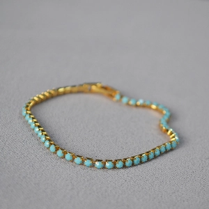 Macro detail of gold-plated bracelet featuring turquoise beads with claw setting