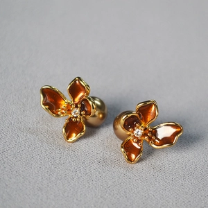 Macro detail of amber enamel flower earrings with champagne tones and gold plating
