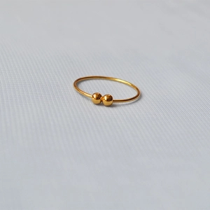 Detailed close-up of a brass gold-plated double bead minimalist ring on gray fabric