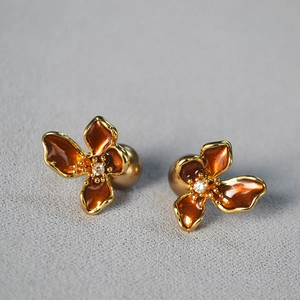 Detail of flower stud earrings with orange enamel petals and a sparkling zircon center