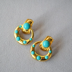 Detailed view of vintage gold-plated brass earrings with turquoise bead inlay