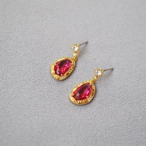 Detail of pear-cut red ruby crystal earrings with vintage gold border and small diamonds