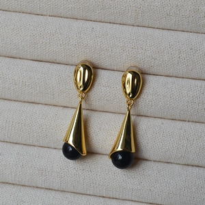 Close-up of gold textured metal earrings with teardrop black onyx stones on display