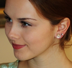 Detailed view of white mother of pearl clover earrings worn by a model in warm light