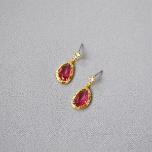 Detail of vintage teardrop red crystal earrings with gold plating and white zircon accents