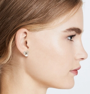 Close-up of white shell clover flower earring on model's ear showing delicate pearl texture