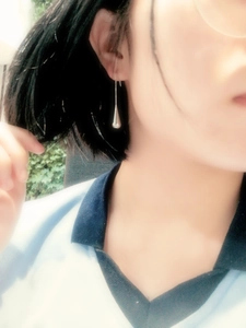 Detail view of silver teardrop earrings on model with sleek metallic mirror finish