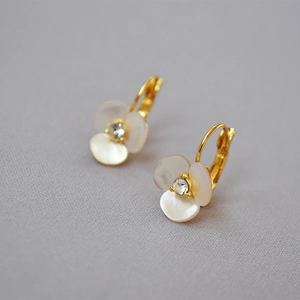 Macro shot of gold clover earrings with white mother-of-pearl petals and center diamond