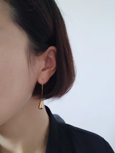 Detailed view of polished gold teardrop earrings hanging elegantly on a model