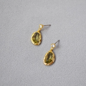 Detail of drop-shaped earrings with olive green crystal and gold plated brass setting