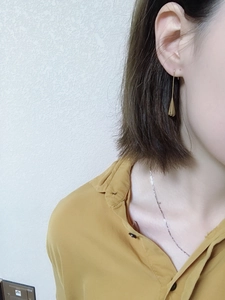 Close-up of gold drop earrings on model with sleek brass waterdrop design