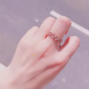 Gros plan sur une bague marguerite en or rose sertie de 110 zircons sur la main