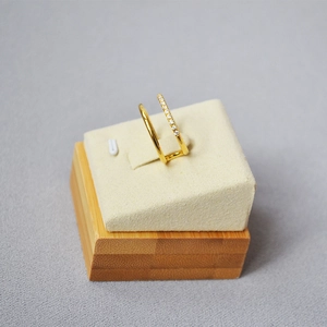 Detail of a gold double-layered ring with sparkling zircons on a beige velvet display