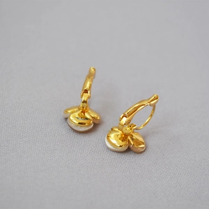 Detail of clover earrings with white mother-of-pearl petals and golden finish