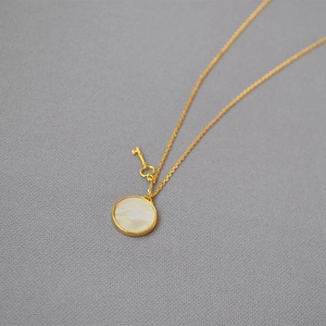 Elegante vergoldete Halskette mit weißem Muschel-Anhänger und kleinem Schlüssel-Charm