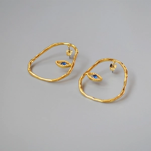 Detailed macro of gold plated abstract eye earrings with a deep blue center stone