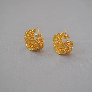 Gold-plated woven hollow earrings in a half-hoop design on neutral fabric backdrop