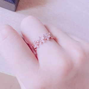 Gros plan détaillé d'une bague fleur en or rose avec micro-pavé de zircons sur un doigt