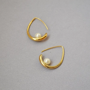 Minimalist golden teardrop earrings with elegant white pearl inlay on textured gray fabric