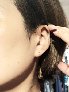 Detailed view of long gold drop earrings with a polished minimalist aesthetic on a model