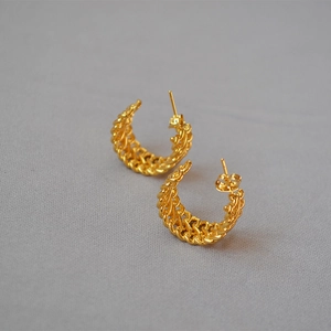 Elegant gold woven C-shaped stud earrings with twisted rope texture on grey fabric