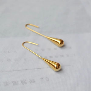 Detail of elegant gold-plated brass water drop earrings with a sleek minimalist finish