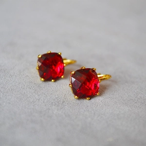 Détail macro de boucles d'oreilles en cristal rouge carré avec monture dorée chic