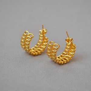 Macro detail of gold-plated braided hollow hoop earrings with textured weave design