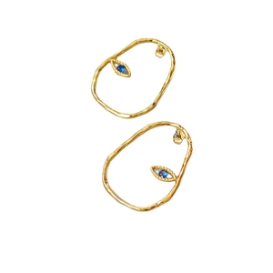 Irregular gold oval hoop earrings with blue eye charms on a clean white background