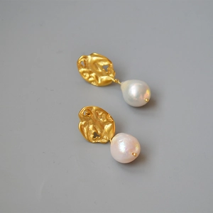Macro view of gold withered leaf earrings featuring large baroque freshwater pearls
