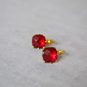 Vue macro de boucles d'oreilles vintage avec pierre carrée rouge et griffes dorées