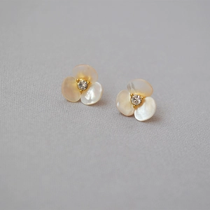 Macro shot of white shell clover earrings with center crystal in gold plating