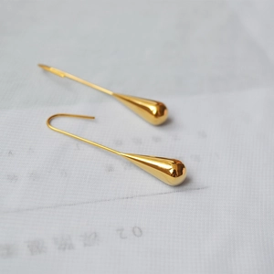 Detailed view of teardrop earrings with high-polished gold plating and long hook design