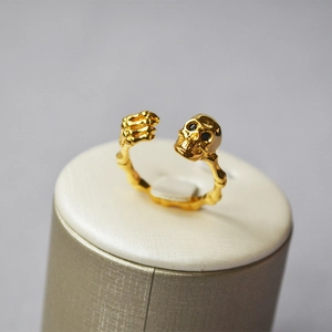 Punk style 18K gold plated skull and skeleton hand open ring on a display stand
