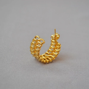 Macro shot of gold-plated twisted chain texture on C-shaped earring with butterfly back