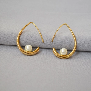 Elegant gold-tone drop hook earrings featuring round white pearls on a grey background