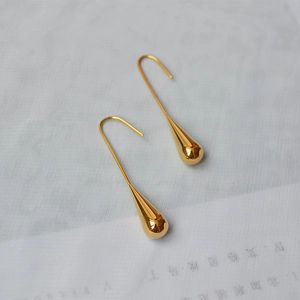 Detailed view of teardrop earrings with a smooth polished gold finish and elegant hooks