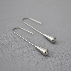 Macro detail of silver-colored teardrop earrings with elegant long ear hooks