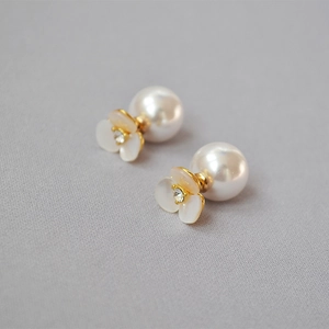 Detailed view of white shell clover earrings with large pearl back and gold plating