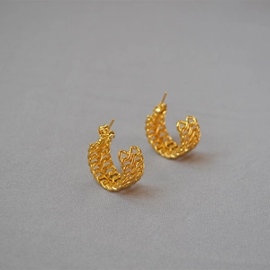 Detail of gold C-shaped earrings showing the intricate braided texture and mesh design