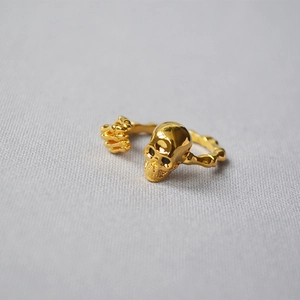 Macro view of 18K gold plated punk skull ring with skeletal bone hand design