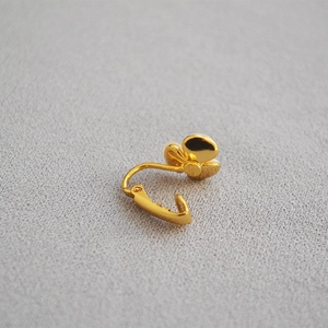 Detailed view of gold-tone clover petal clip-on earring back with a smooth polished finish