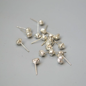 Detailed close-up of irregular silver stud earrings with molten lava rock texture