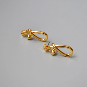 Detailed close-up of 18K gold-plated brass stud earrings featuring a twisted knot design