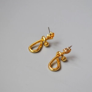 Detailed macro shot of 18K gold-plated knotted stud earrings with butterfly back
