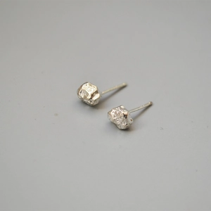 Detailed view of silver stud earrings with irregular volcanic rock texture design